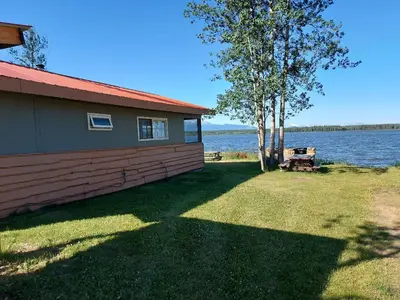 a house with a picnic table next to a lake at Escott Bay Resort in Anahim Lake