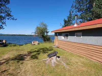 a house with a bird sculpture next to a body of water at Escott Bay Resort in Anahim Lake