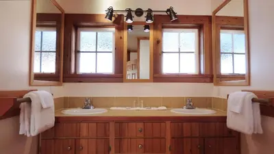 a bathroom with two sinks and two mirrors at Seine Boat Inn in Alert Bay
