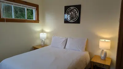 a bedroom with a white bed with two lamps on tables at Seine Boat Inn in Alert Bay