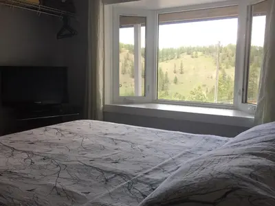 a bedroom with a bed and a large window at WhiteTail Suite - Misty River Lodge - in Radium Hot Springs