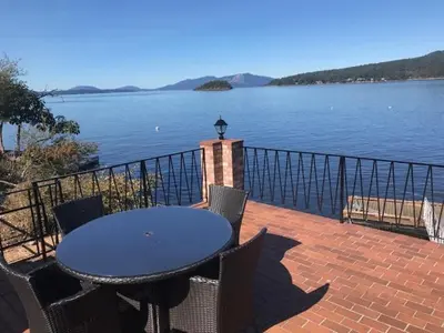 a table and chairs on a patio with a view of the water at Ocean Front Retreat with Stunning Water Views in Victoria