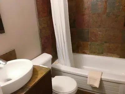 a bathroom with a sink and a toilet and a bath tub at Canterbury Inn in Invermere