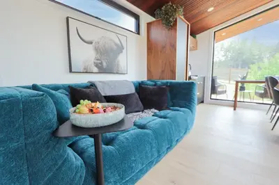 a blue couch in a living room with a bowl of fruit on a table at Refuge Bay Caelum Cabin Luxury Off Grid Escape in Cherhill