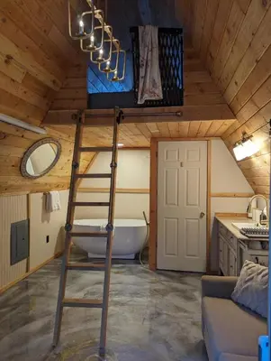 a bathroom with a ladder and a bath tub in a room at Tree Ring Cabin on 33 Acre Farm in Powell River
