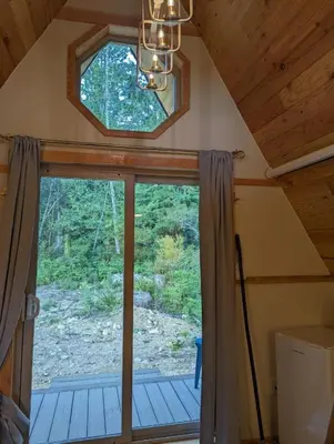 a room with a large window in a cabin at Tree Ring Cabin on 33 Acre Farm in Powell River
