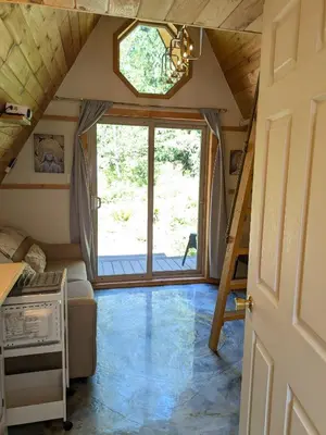 a tiny house with a large window and a staircase at Tree Ring Cabin on 33 Acre Farm in Powell River