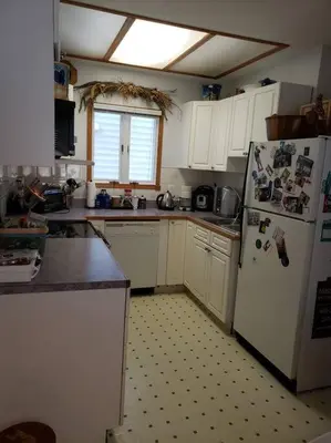 a kitchen with white cabinets and a white refrigerator at Mission Historical Home in Calgary
