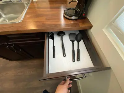 a person is reaching into a kitchen drawer with utensils at New Dt Apartment Walk To All in Edmonton