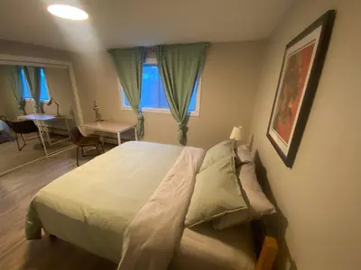 a bedroom with a bed and a table and a window at Brand New Modern Flat 2br1ba Whyte And University in Edmonton