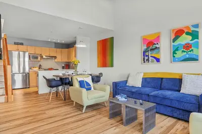 a living room with a blue couch and a kitchen at Freshly Remodeled - 2 King Beds- Breathtaking Views in Canmore