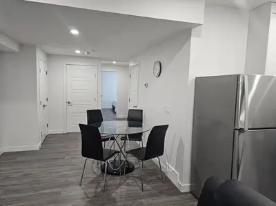 a dining room with a table and chairs and a refrigerator at New 2 bdrm basement suite Seton in Calgary