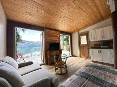 a living room with a couch and a table and a kitchen at Private Ozarks Island Retreat in Agassiz
