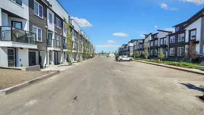 an empty street with houses and a car on the road at Cozy place to stay in south Calgary in Calgary