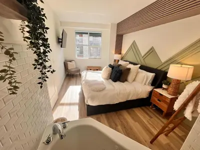 a bedroom with a bed and a bath tub at Three Peaks Getaway Jacuzzi Suite - sleeps 4 in Canmore