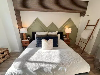 a bedroom with a large white bed with blue pillows at Three Peaks Getaway Jacuzzi Suite - sleeps 4 in Canmore