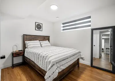 a white bedroom with a bed and a mirror at Mountain Hideaway Two Bedrooms Free Park Pass in Cochrane