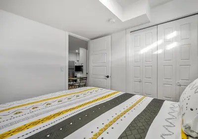 a white bedroom with a bed and two white doors at Mountain Hideaway Two Bedrooms Free Park Pass in Cochrane
