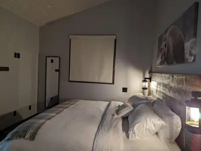a bedroom with a large bed with white pillows at Skyline Suite 2Bdrm King in Valemount