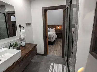 a bathroom with a bed and a sink and a mirror at Skyline Suite 2Bdrm King in Valemount