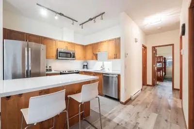 a kitchen with wooden cabinets and white appliances at Deer Run by Outpost Whistler in Whistler