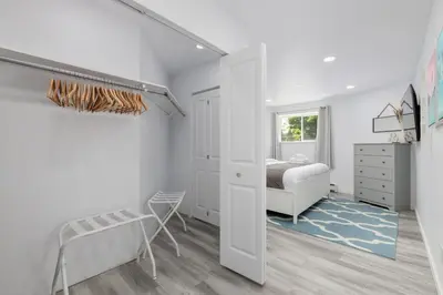 a bedroom with white walls and a bed and a staircase at Serenity 1BR & 1 DEN Home at Folsom Ave in Coquitlam