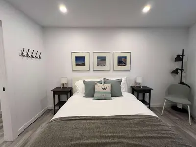 a bedroom with a large bed with three pictures on the wall at Serenity 1BR & 1 DEN Home at Folsom Ave in Coquitlam