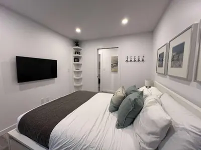 a bedroom with a large bed and a flat screen tv at Serenity 1BR & 1 DEN Home at Folsom Ave in Coquitlam
