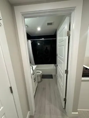 a bathroom with a toilet and a sink in a room at Cozy 1 bedroom basement apartment in Airdrie