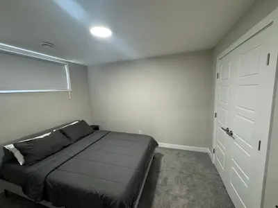 a bedroom with a bed and a white door at Cozy 1 bedroom basement apartment in Airdrie
