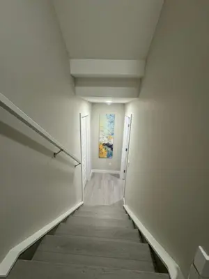 a hallway with a staircase with a painting on the wall at Cozy 1 bedroom basement apartment in Airdrie