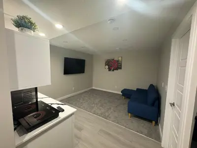 a living room with a blue chair and a tv at Cozy 1 bedroom basement apartment in Airdrie