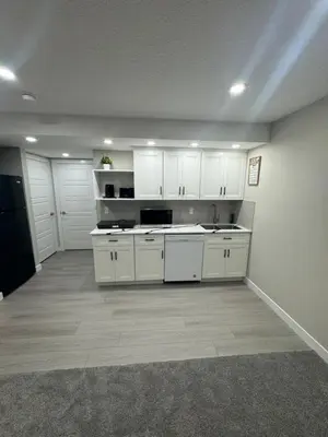 an empty kitchen with white cabinets and a sink at Cozy 1 bedroom basement apartment in Airdrie