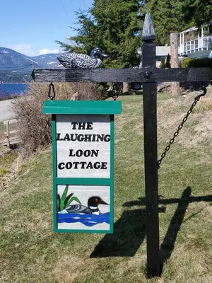 a sign on a wooden fence with a sign for a lochalling loch at West facing Waterfront Cottage with private beach & buoy & dock access in Blind Bay