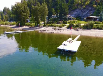 a small white boat in a body of water at West facing Waterfront Cottage with private beach & buoy & dock access in Blind Bay