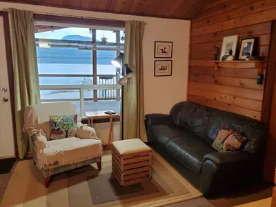 a living room with a leather couch and a chair at West facing Waterfront Cottage with private beach & buoy & dock access in Blind Bay
