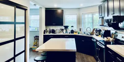 a kitchen with black cabinets and a white counter top at Vancouver Airport 7 mins away Cozy room Richmond near YVR in Richmond