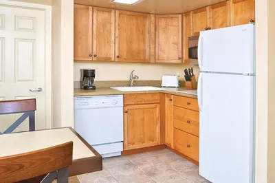a kitchen with a white refrigerator and wooden cabinets at 2 Bd Worldmark Canmore Banff Condo in Canmore