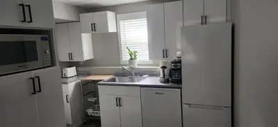 a white kitchen with a sink and a refrigerator at The Bainbridge Studio in Burnaby