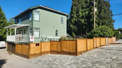 a house with a wooden fence in front of it at The Bainbridge Studio in Burnaby