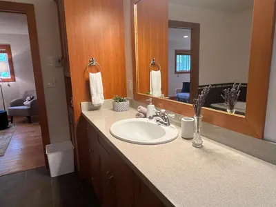 a bathroom with a sink and a large mirror at A Seaside Jacuzzi Escape in Parksville, BC, Canada in Parksville