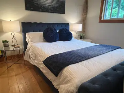 a bedroom with a bed with two blue pillows on it at A Seaside Jacuzzi Escape in Parksville, BC, Canada in Parksville
