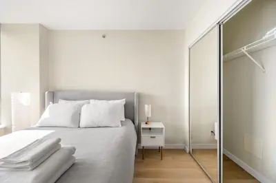 a bedroom with a bed with white sheets and a mirror at Lovely condo with amazing view in Vancouver
