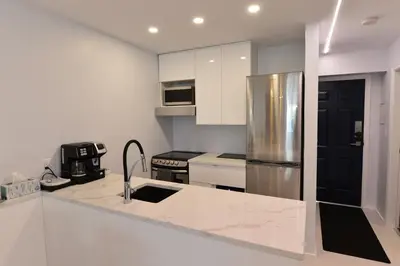 a kitchen with white cabinets and a stainless steel refrigerator at Upscale Modern Apartment in Whistler