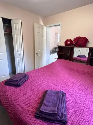 a bedroom with a pink bed with two towels on it at Serenity Bed and Breakfast in Comox