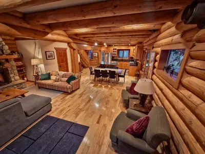 a living room with wooden walls and a dining room at GrizzPaw Lodge - Mountain Resort - 5 Bedroom Chalet - Sleeps 14 People in Golden