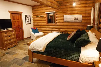 a bedroom with a bed in a room with wooden walls at GrizzPaw Lodge - Mountain Resort - 5 Bedroom Chalet - Sleeps 14 People in Golden