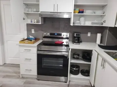 a kitchen with a stove and white cabinets at Entire guest suite in Cochrane, AB in Cochrane