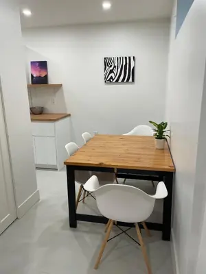a dining room table with a white chair and a table at Spacious Forested Garden Suite in North Vancouver