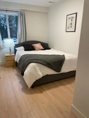 a bedroom with a large bed with a wooden floor at Spacious Forested Garden Suite in North Vancouver